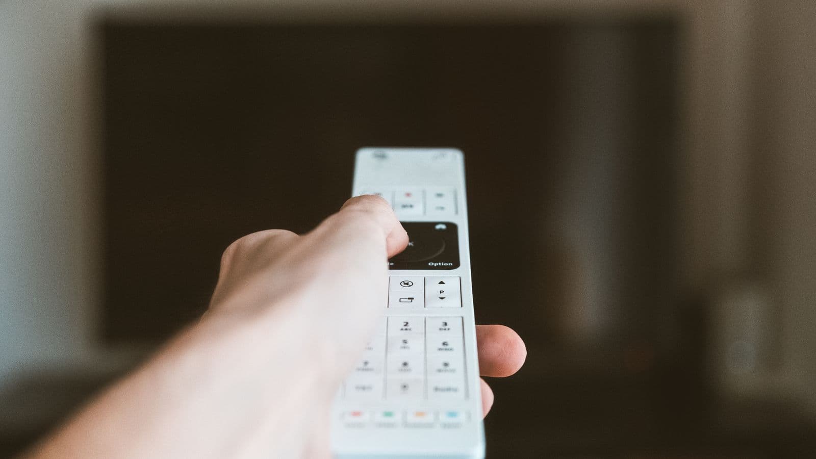 Dłoń z pilotem uruchamia telewizję online po wykupieniu abonamentu